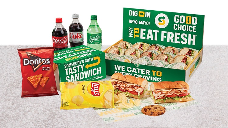 Catering box with bottled soda, chips, sandwich and cookie.