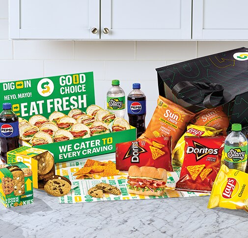 Subway® Catering subs, chips, cookies and Pepsi products on countertop.