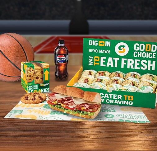 Subway® Catering subs, chips, cookies and a Pepsi bottle on a table by a basketball.