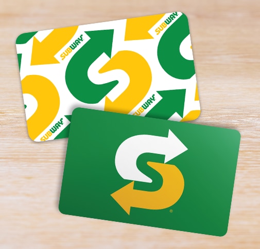 Two Subway gift cards seen overhead on a wooden surface.